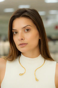 a woman wearing a white top and a gold necklace