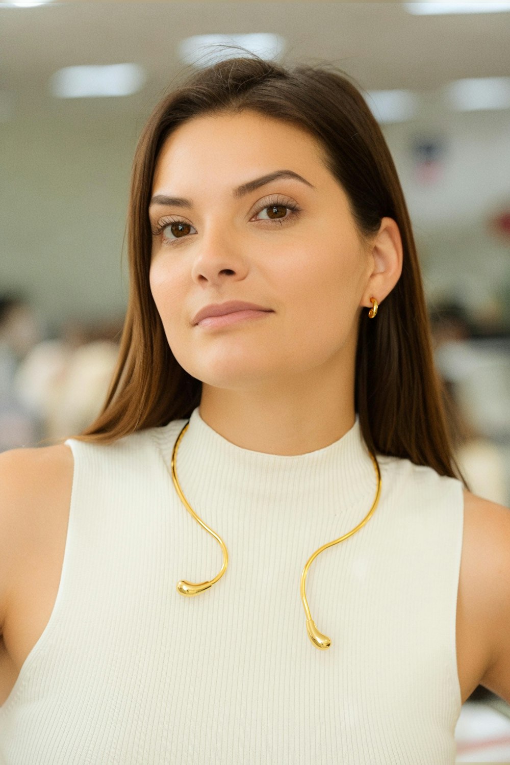 a woman wearing a white top and a gold necklace