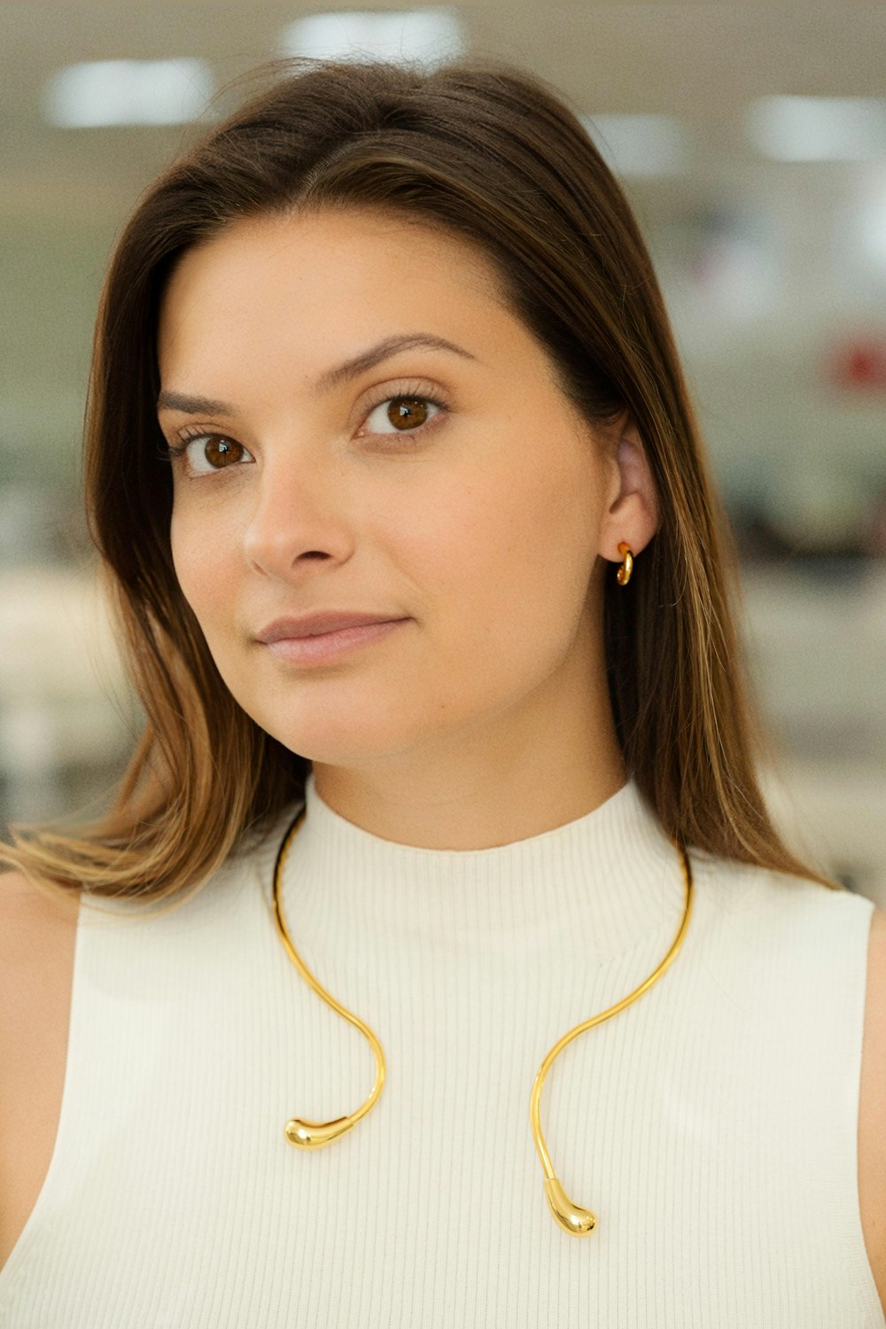 a woman wearing a white top and a gold necklace