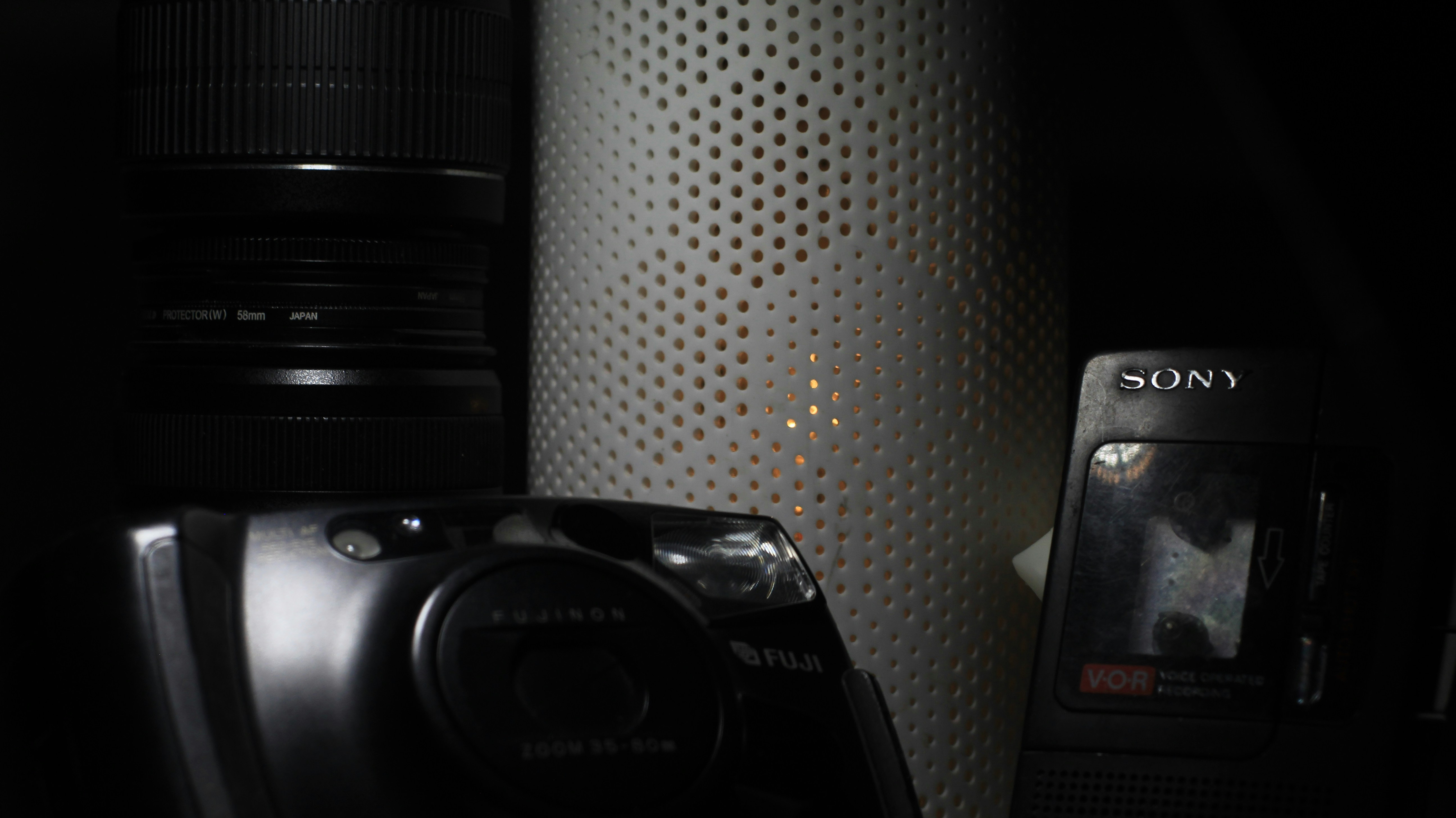 a cell phone sitting next to a camera in a dark room