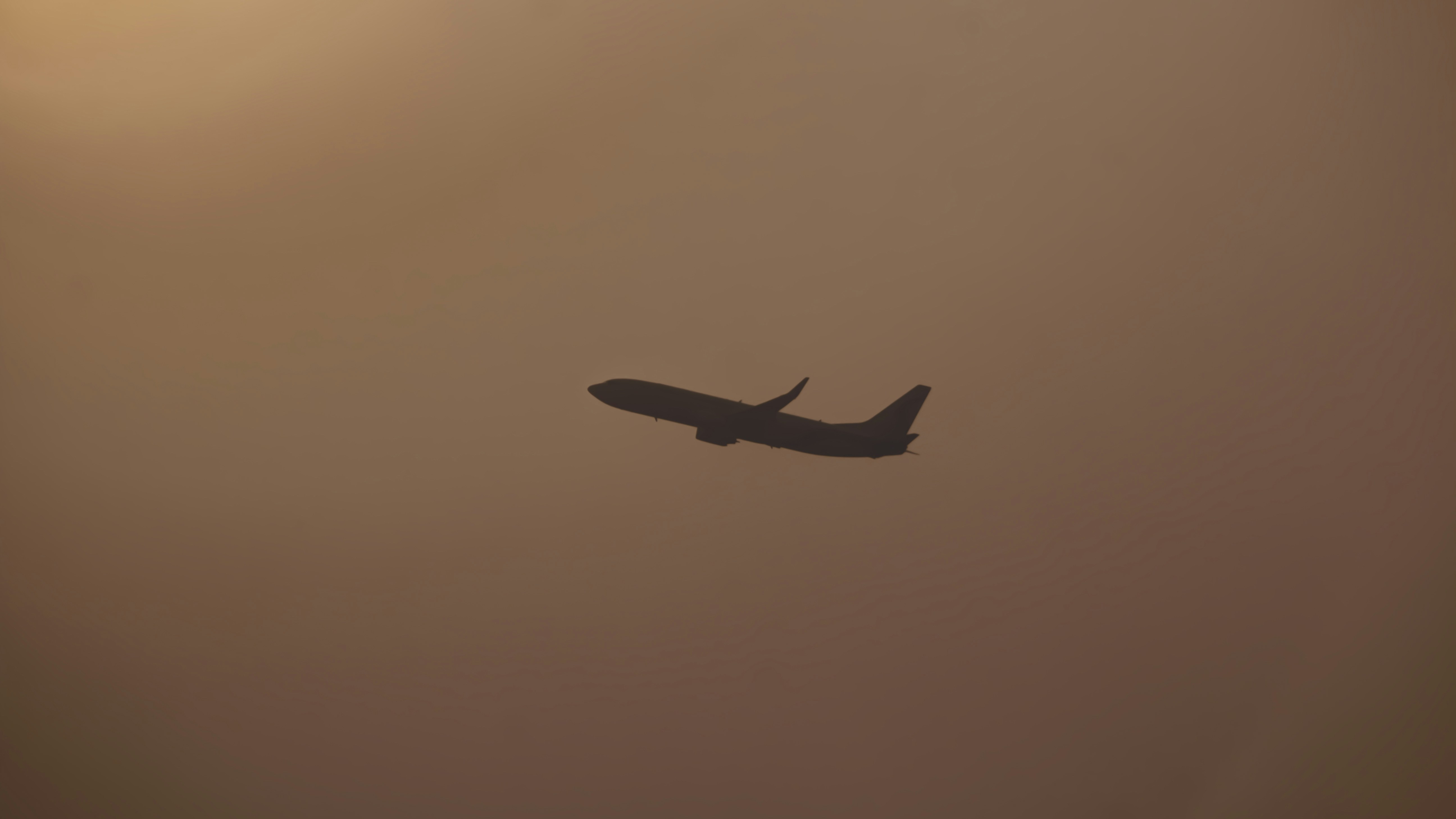 a plane flying in the sky on a hazy day