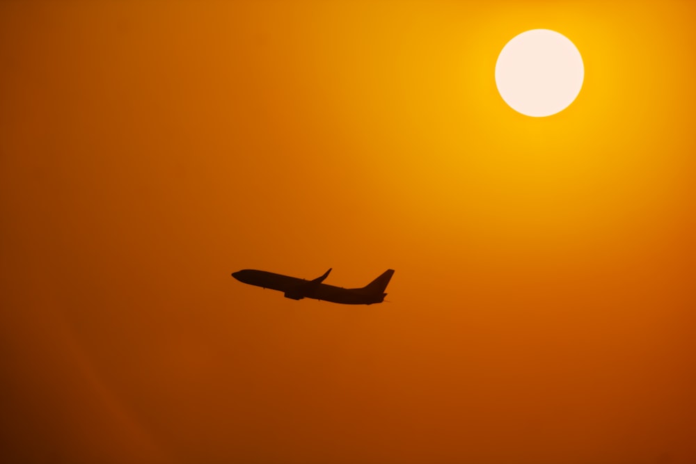 a plane is flying in front of the sun