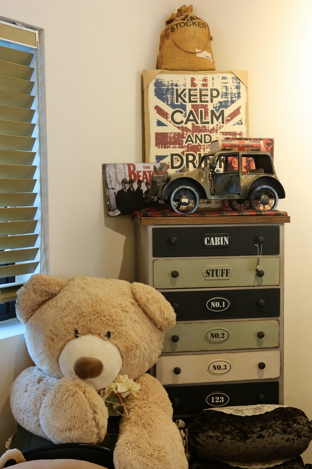 a teddy bear sitting on top of a chest of drawers
