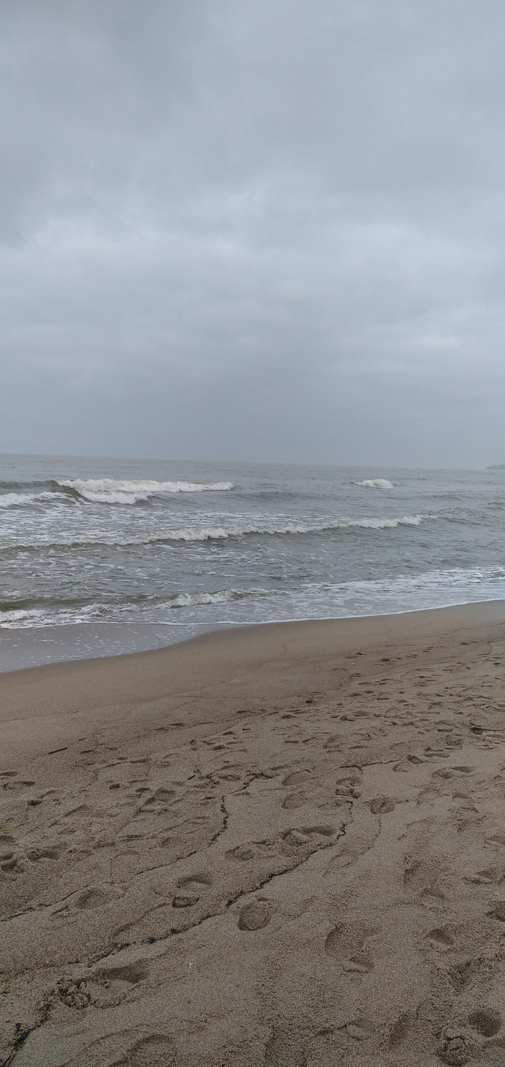 eine Person, die mit einem Surfbrett am Strand spazieren geht