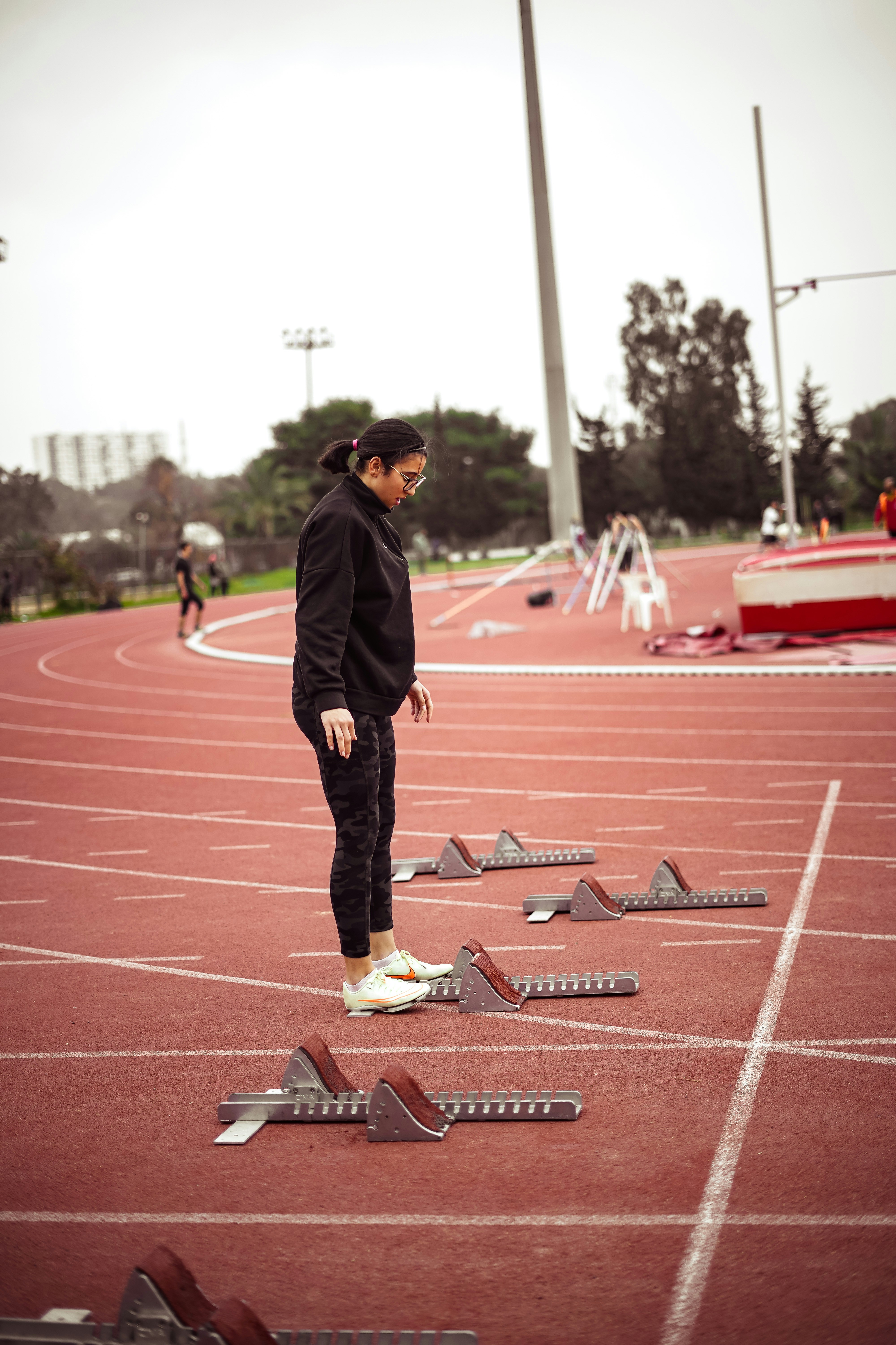 a woman standing on a track surrounded by broken pieces of equipment