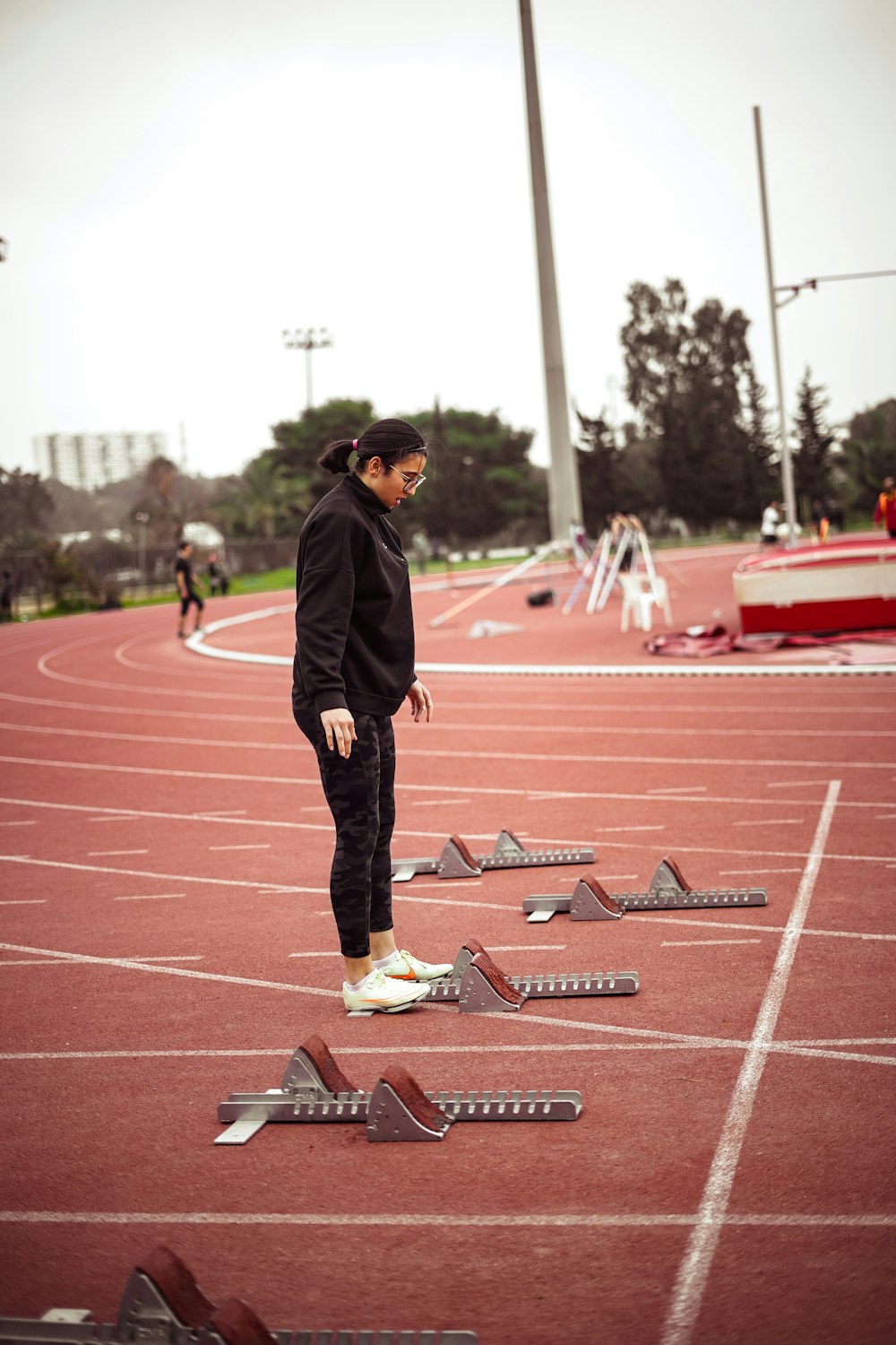 a woman standing on a track surrounded by broken pieces of equipment
