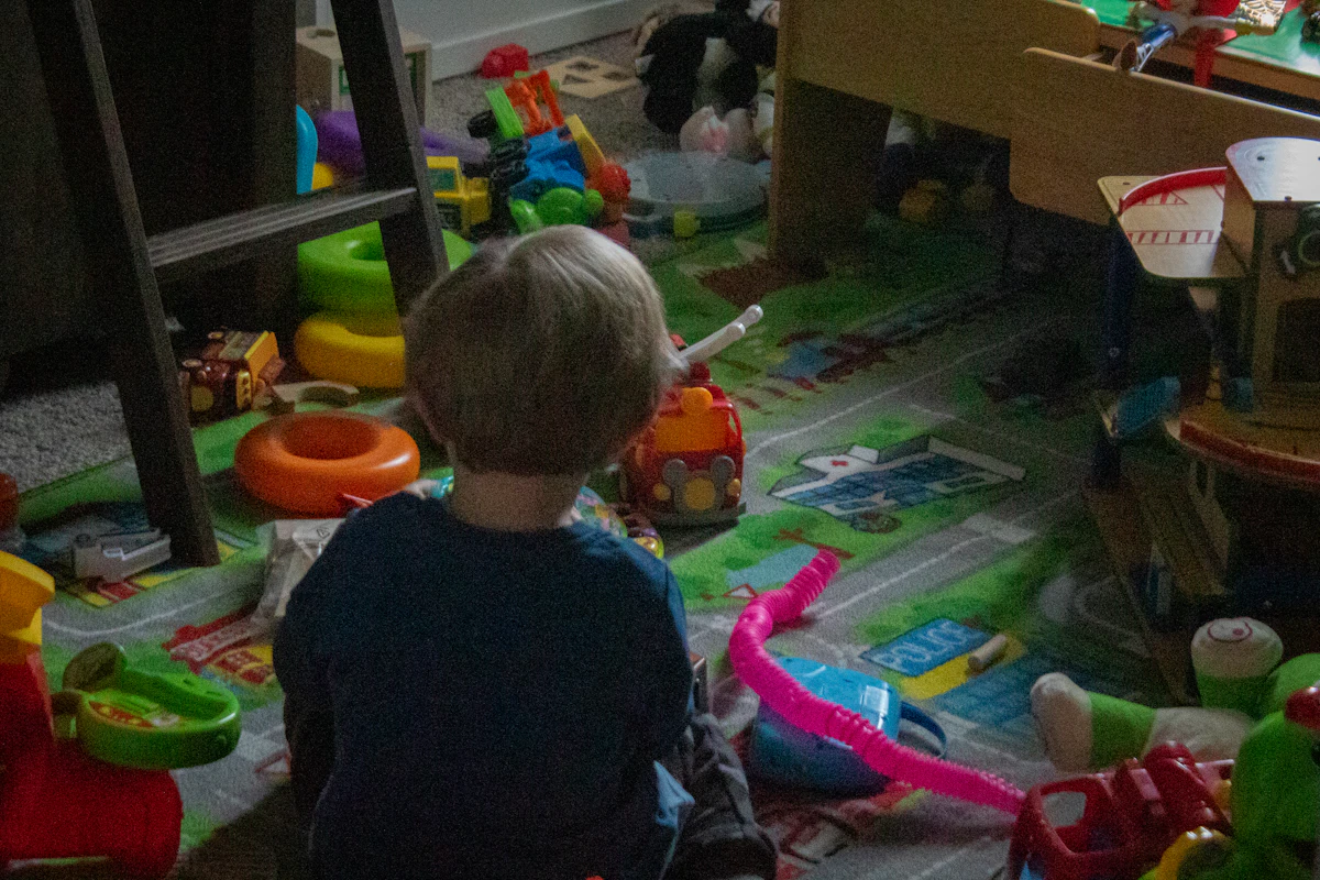 Dziecko bawiące się na podłodze w pokoju pełnym zabawek