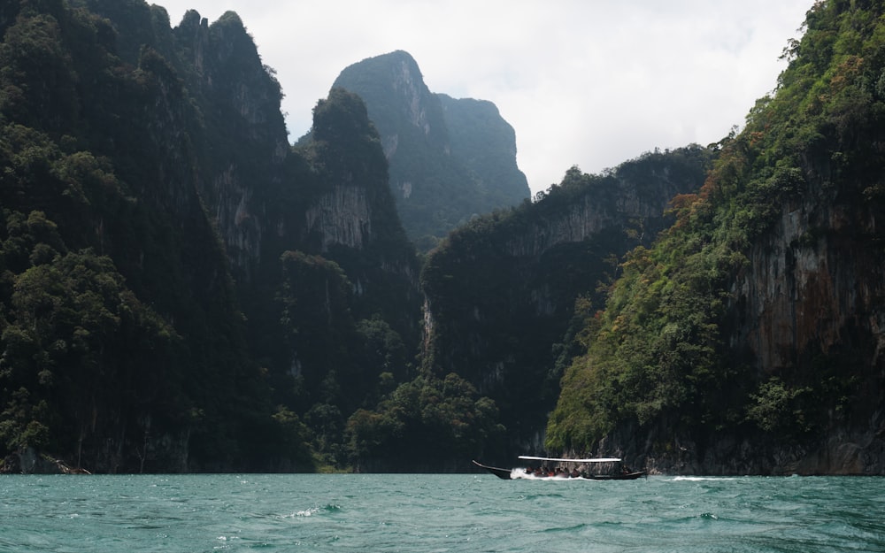 a boat traveling through a river surrounded by mountains