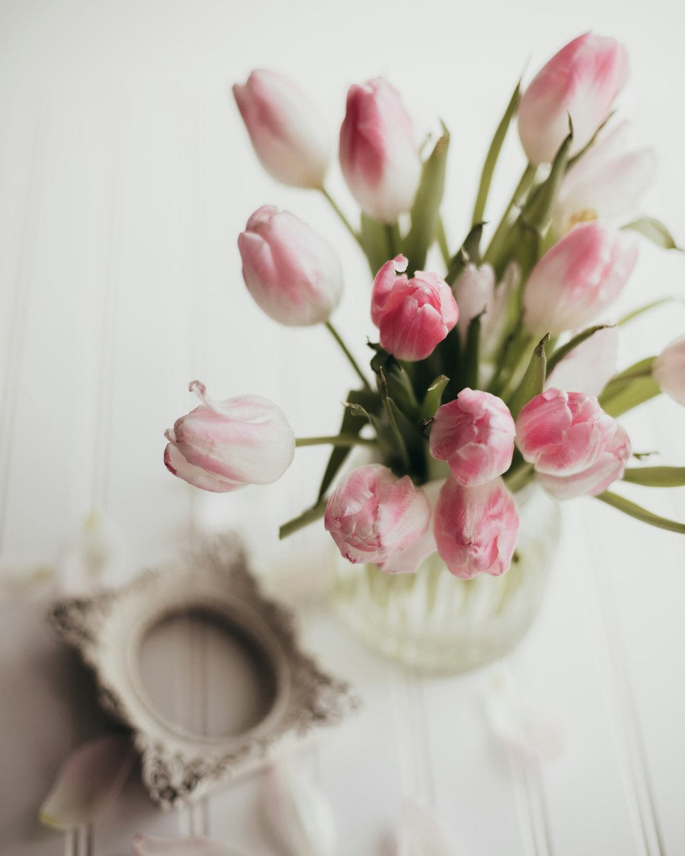 un vase rempli de tulipes roses sur le dessus d’une table
