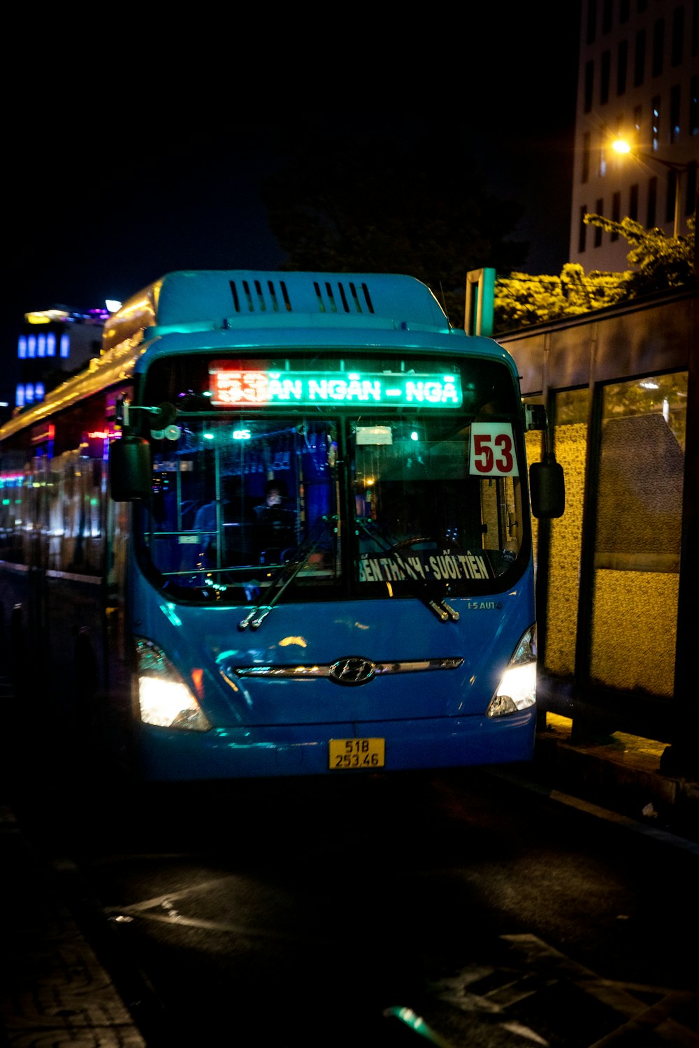 a blue bus driving down a street at night