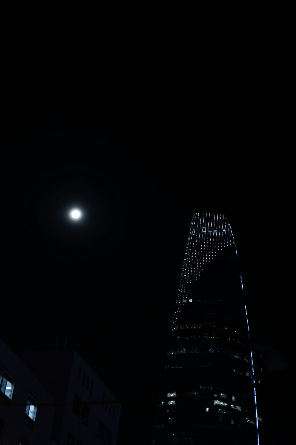 ein sehr hohes Gebäude, das nachts beleuchtet ist