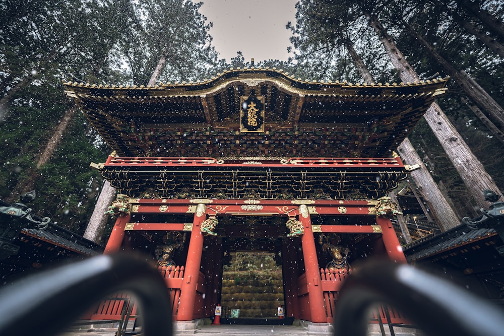 a tall red building sitting in the middle of a forest