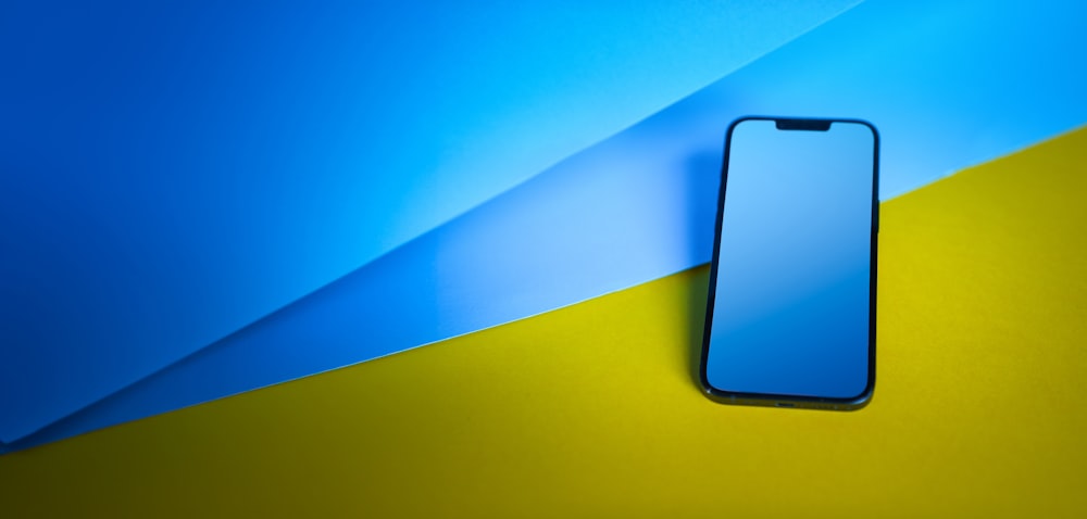 a cell phone laying on top of a blue and yellow background