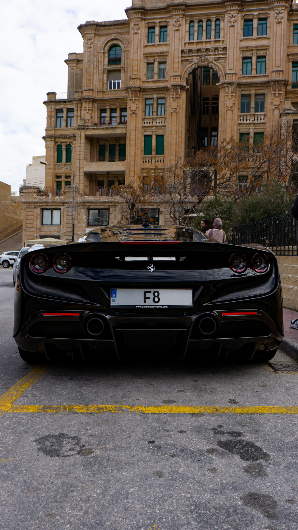 un'auto sportiva nera parcheggiata di fronte a un edificio