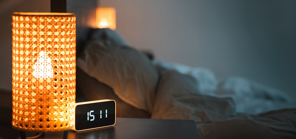 a clock sitting on top of a table next to a lamp