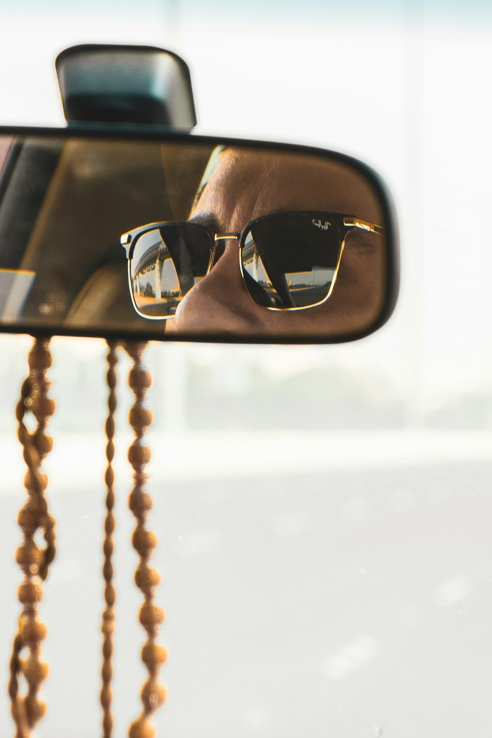 a man wearing sunglasses is reflected in a rear view mirror