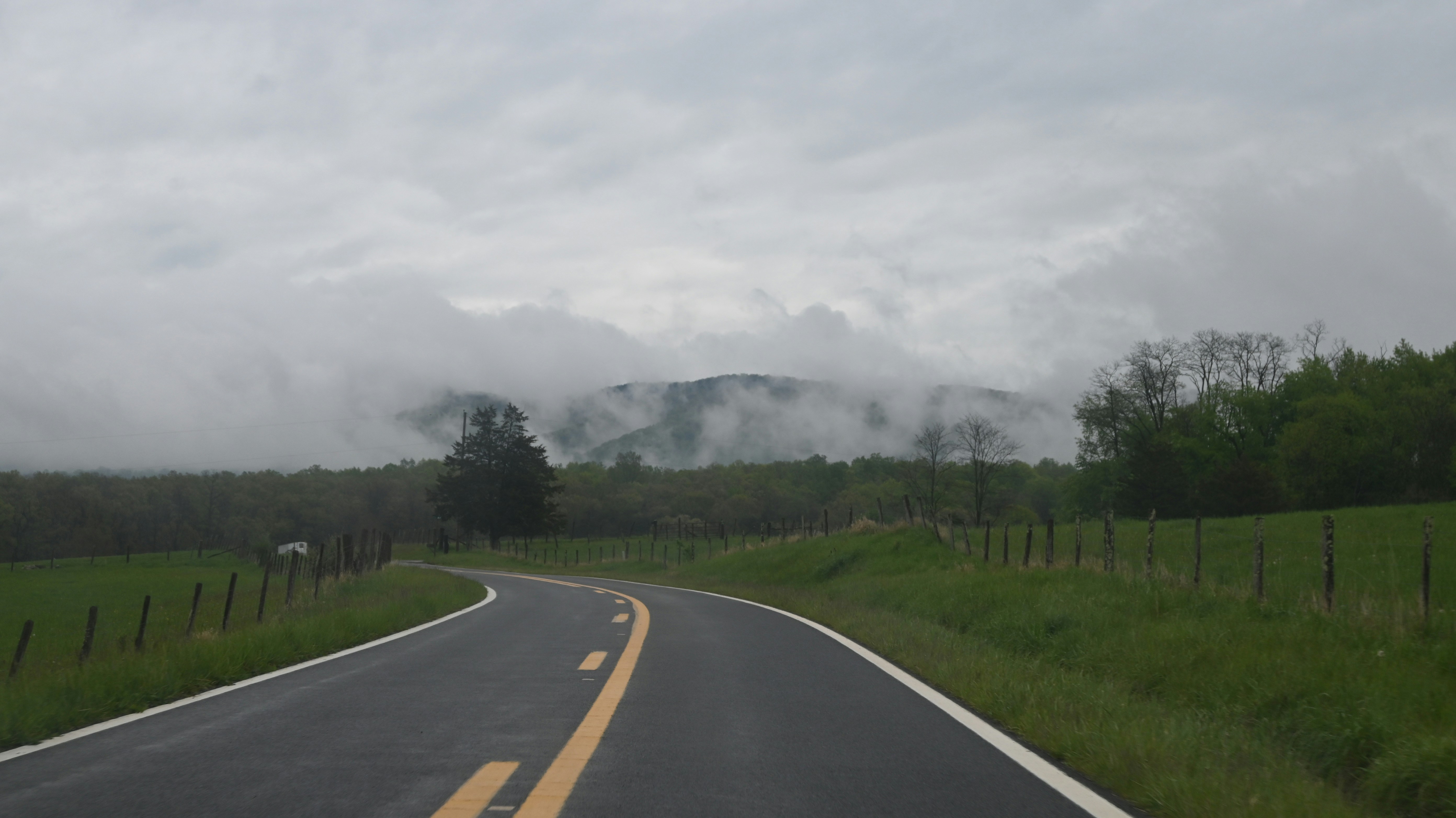 a road with a fence and a field in the background