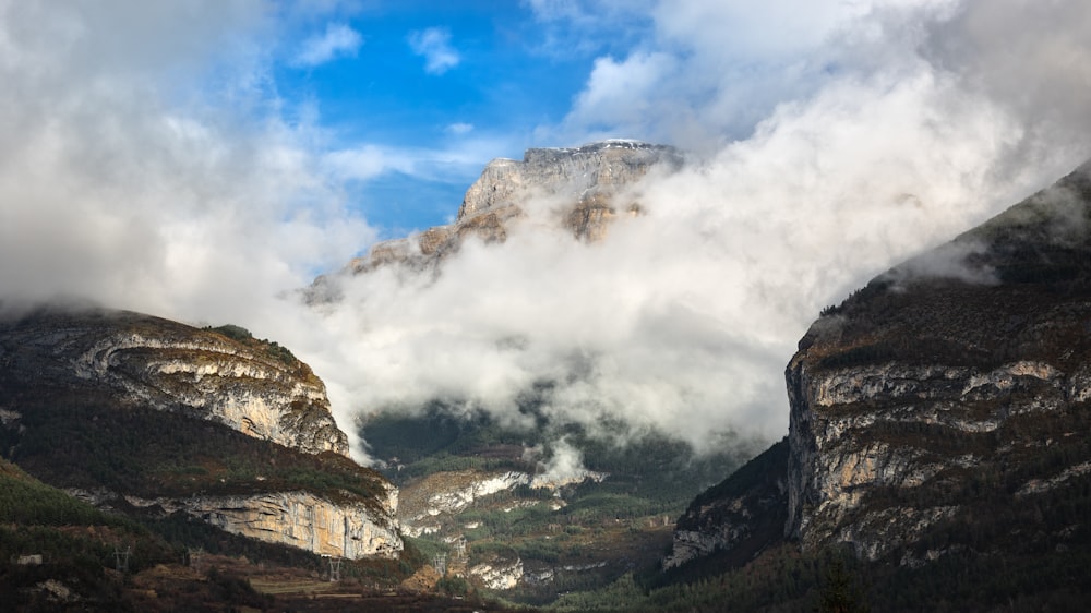 a view of a mountain range with clouds coming out of it