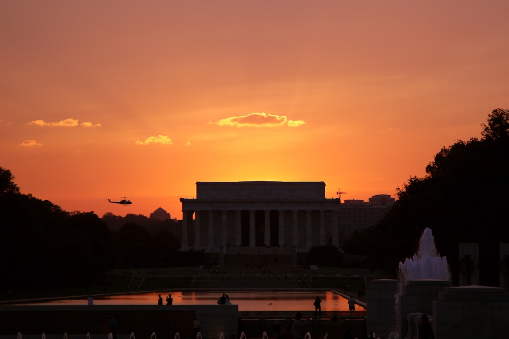 the sun is setting over the lincoln memorial