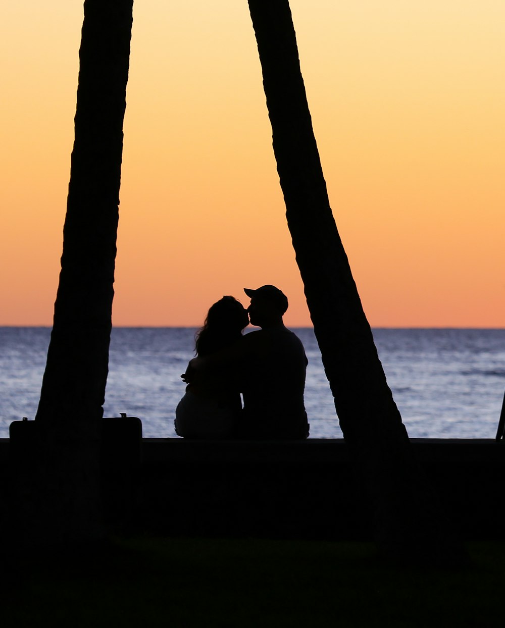 a silhouette of two people sitting on a bench
