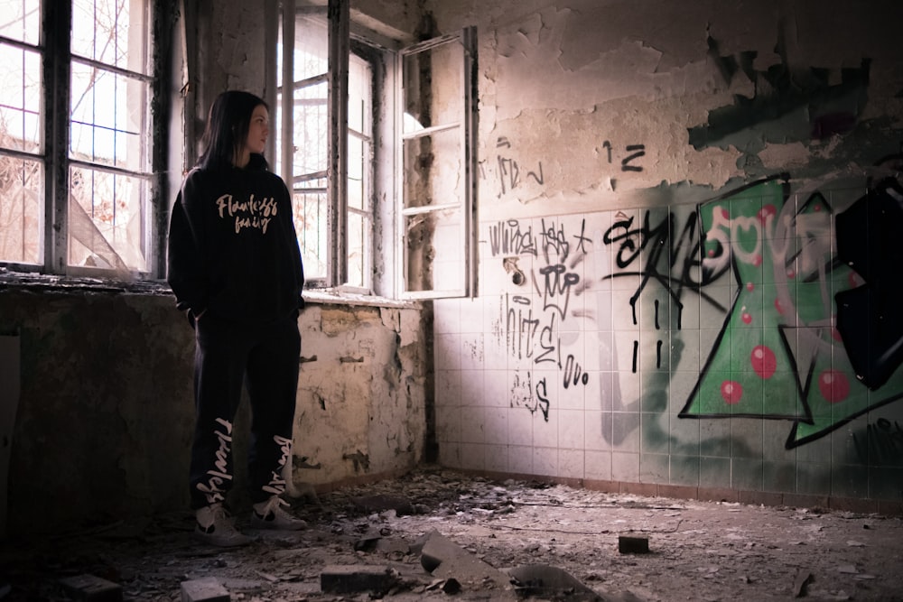 a person standing in a room with graffiti on the walls