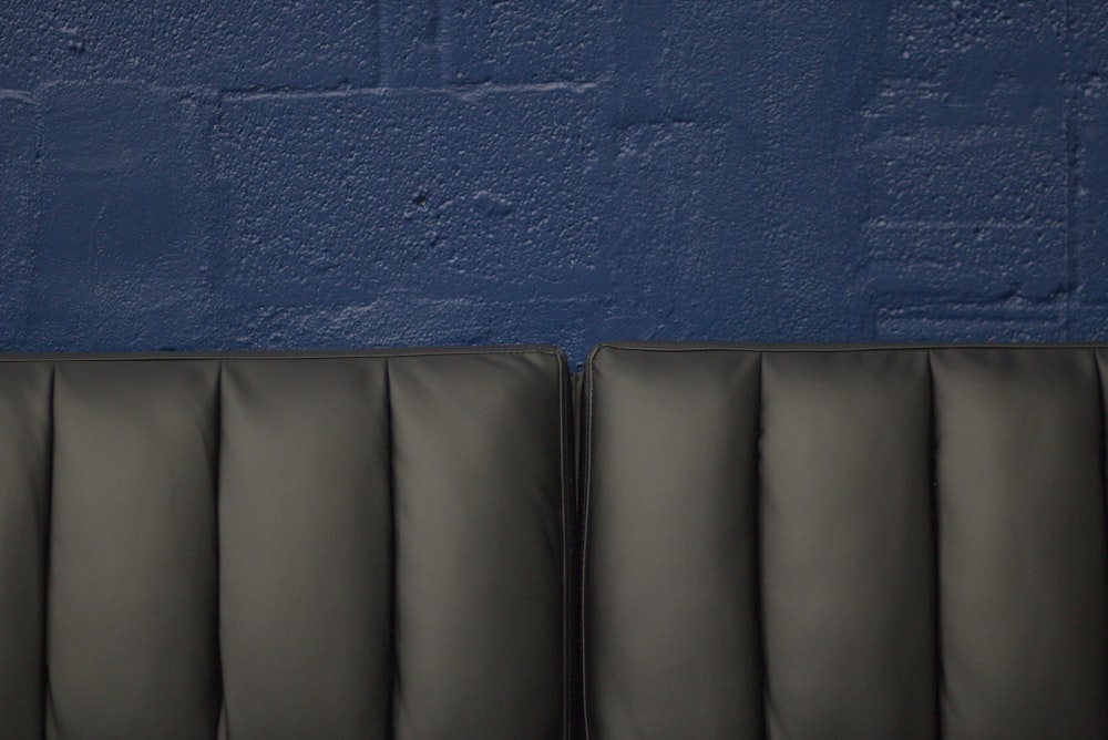 a black leather couch against a blue wall