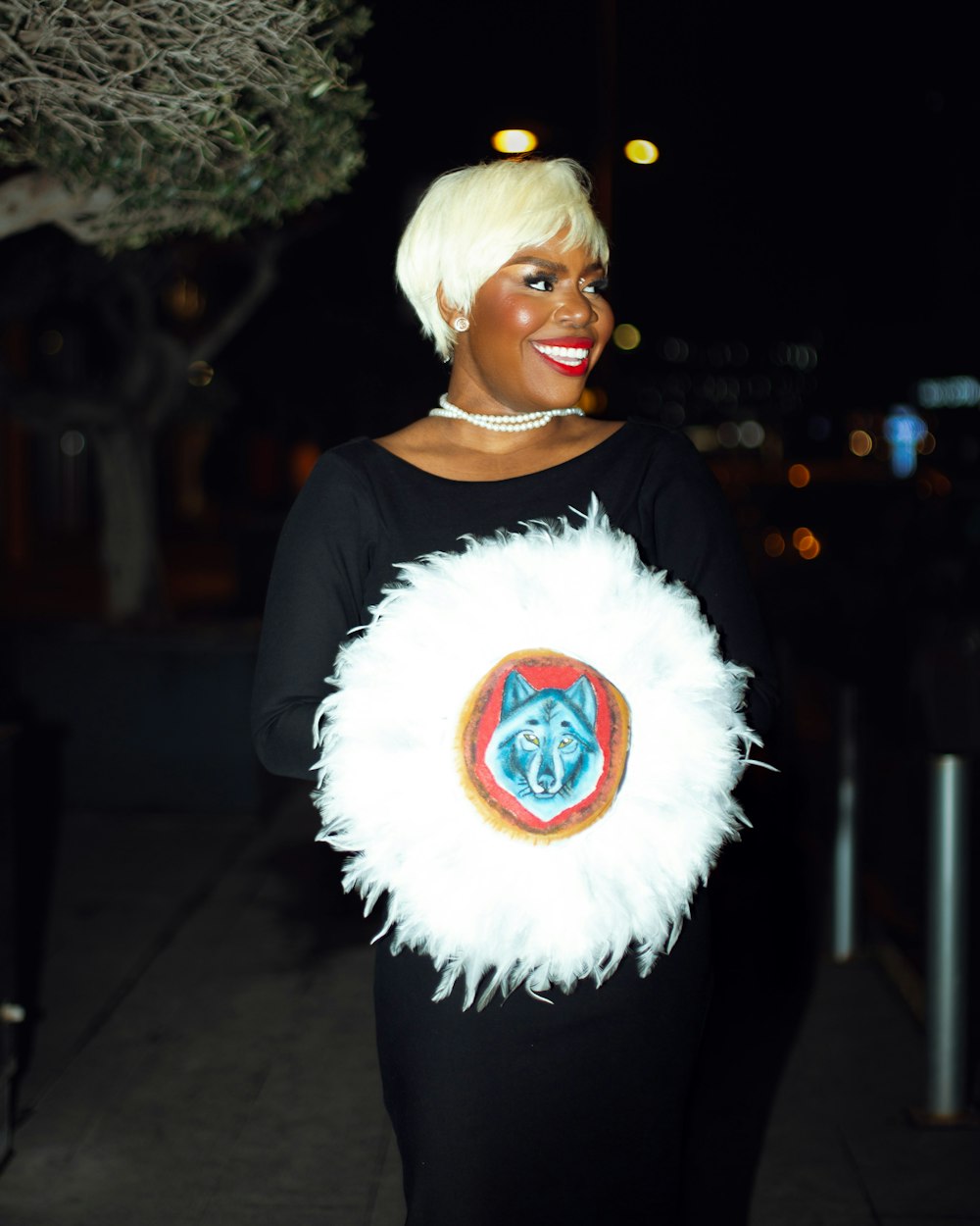 a woman in a black dress holding a white feather bag