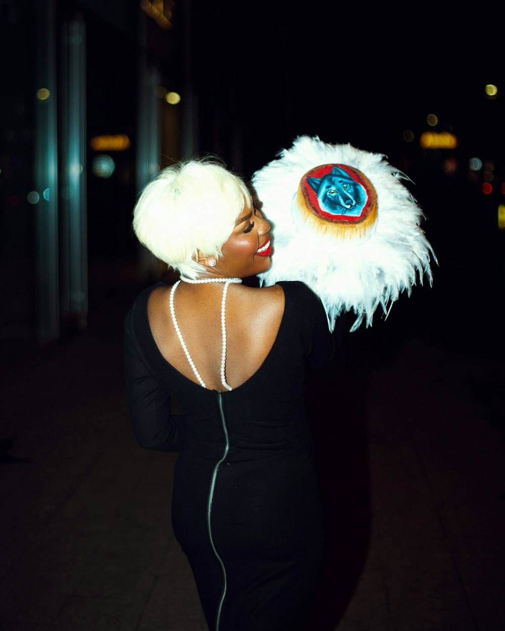 a woman in a black dress with a white feather headpiece