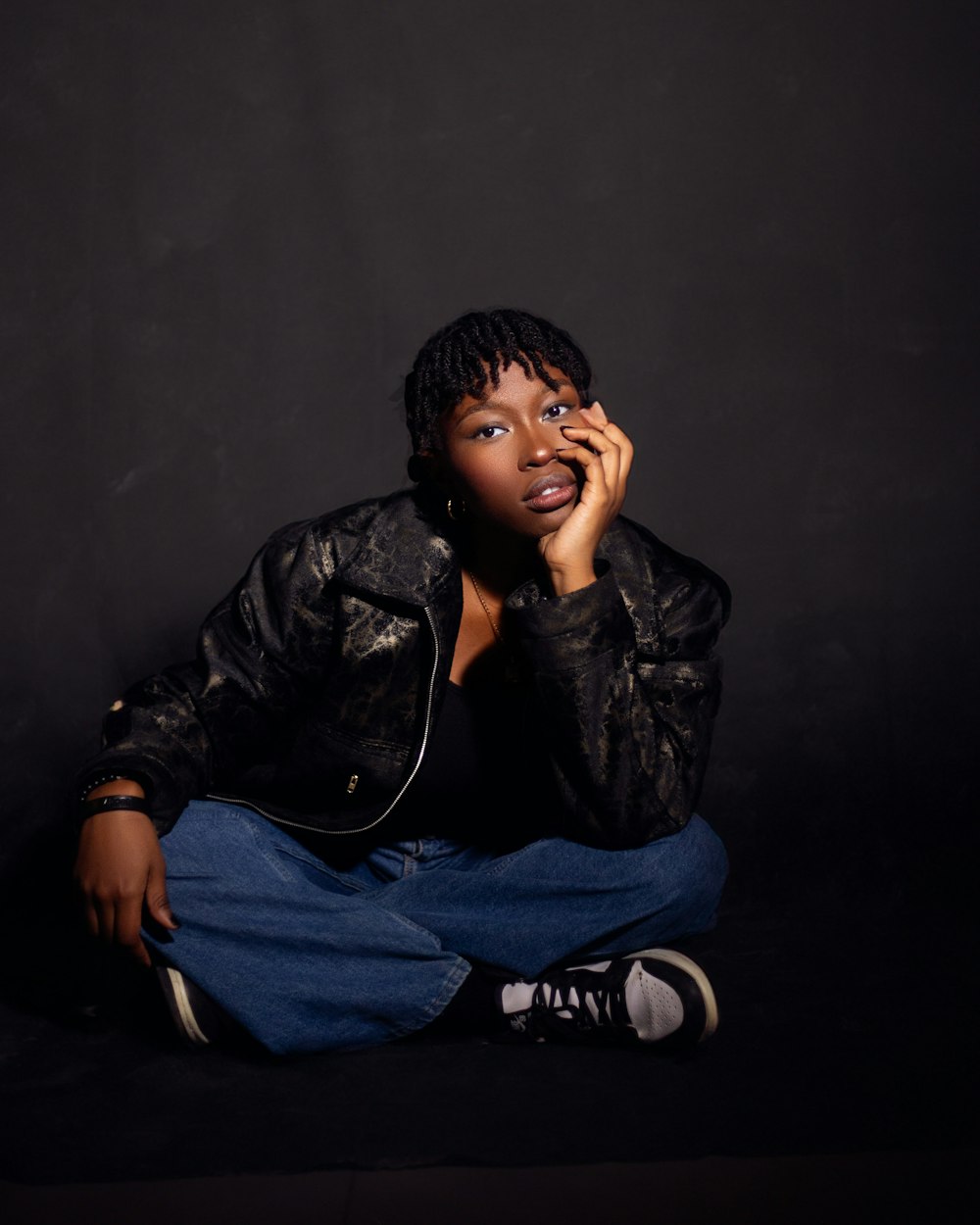 a woman sitting on the ground talking on a cell phone