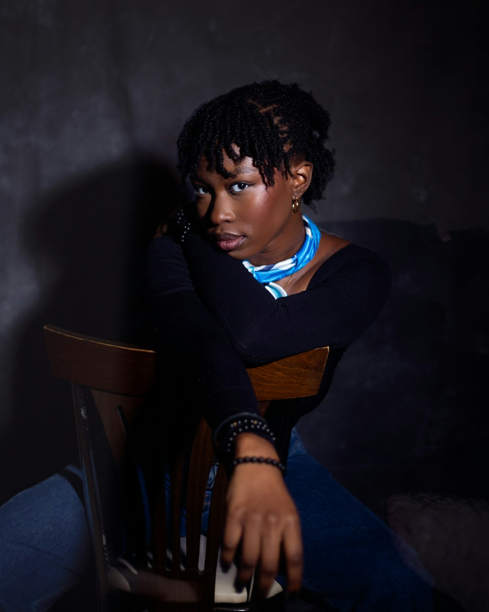 a woman sitting in a chair with her hand on her face