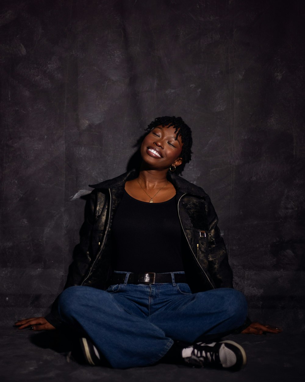 a woman sitting on the floor with her eyes closed