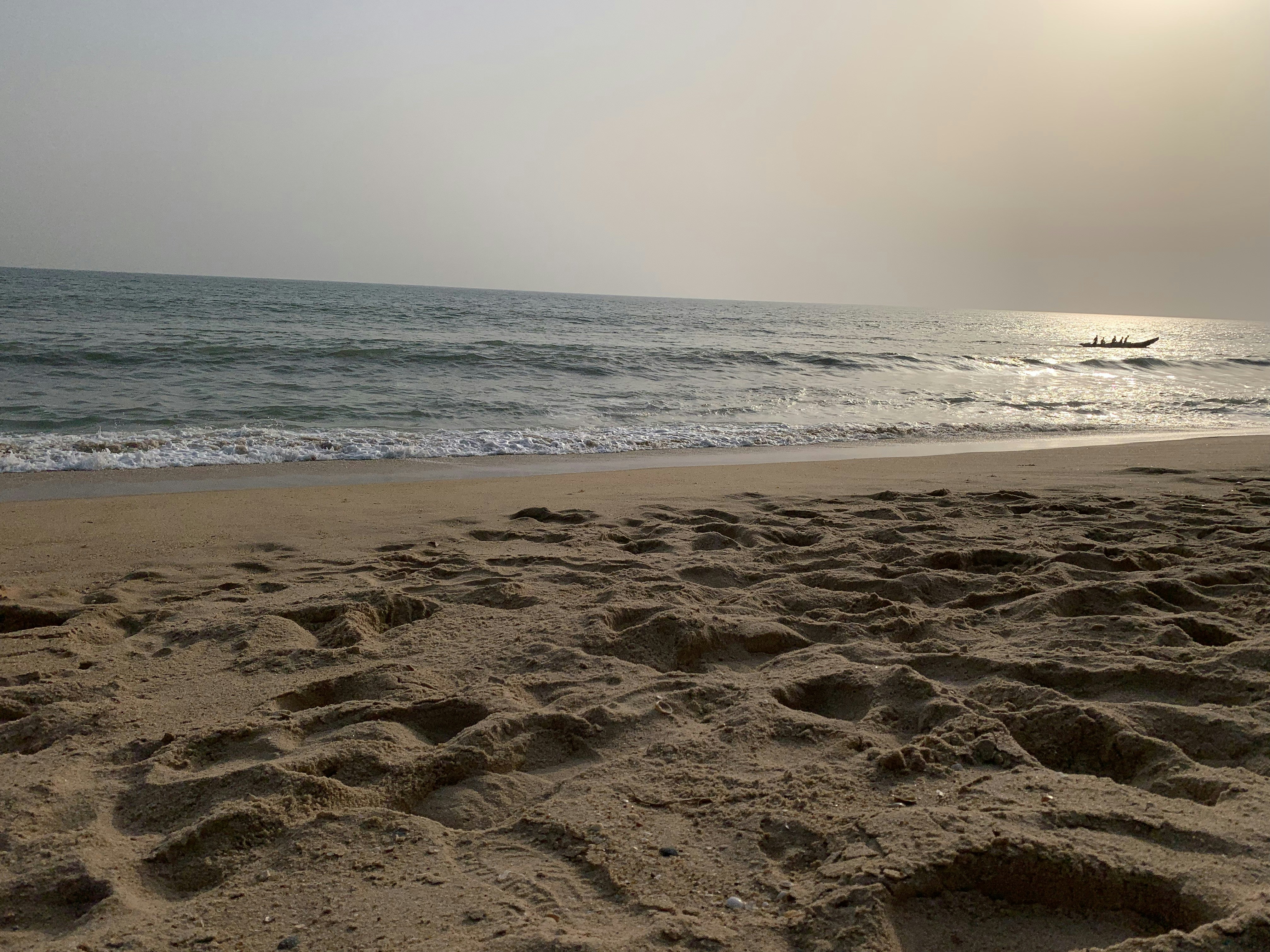 a sandy beach with a boat in the distance, walking at beach