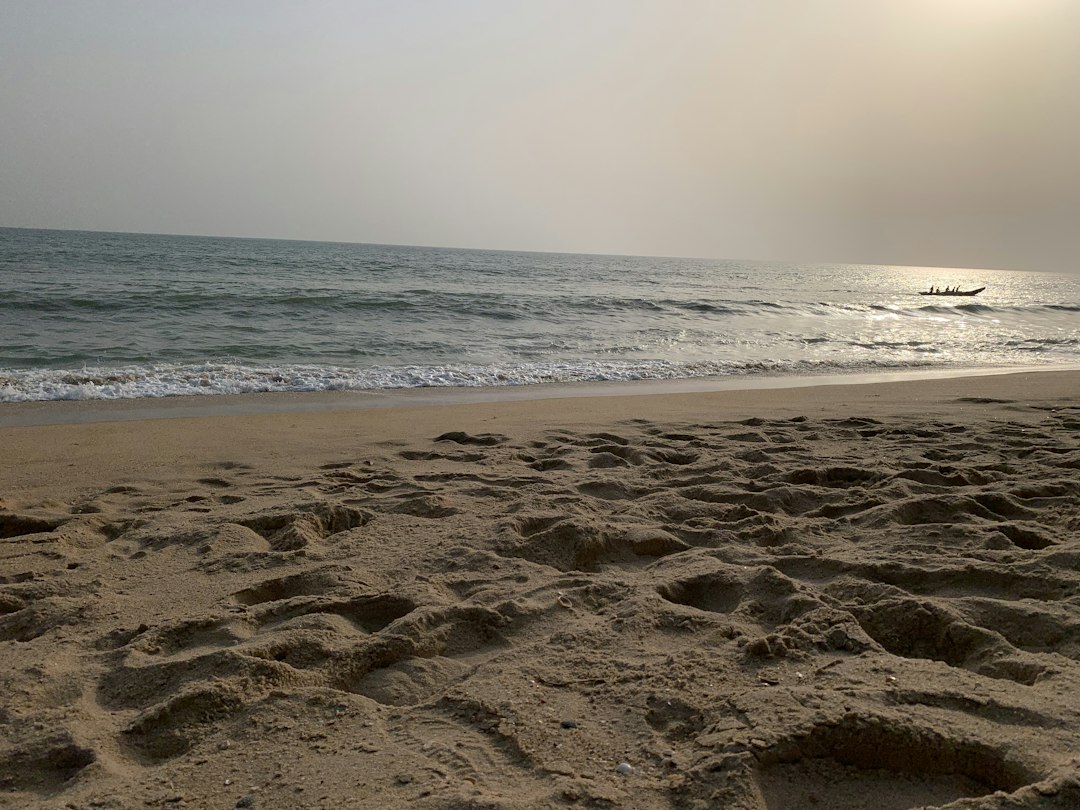 a sandy beach with a boat in the distance, walking at beach