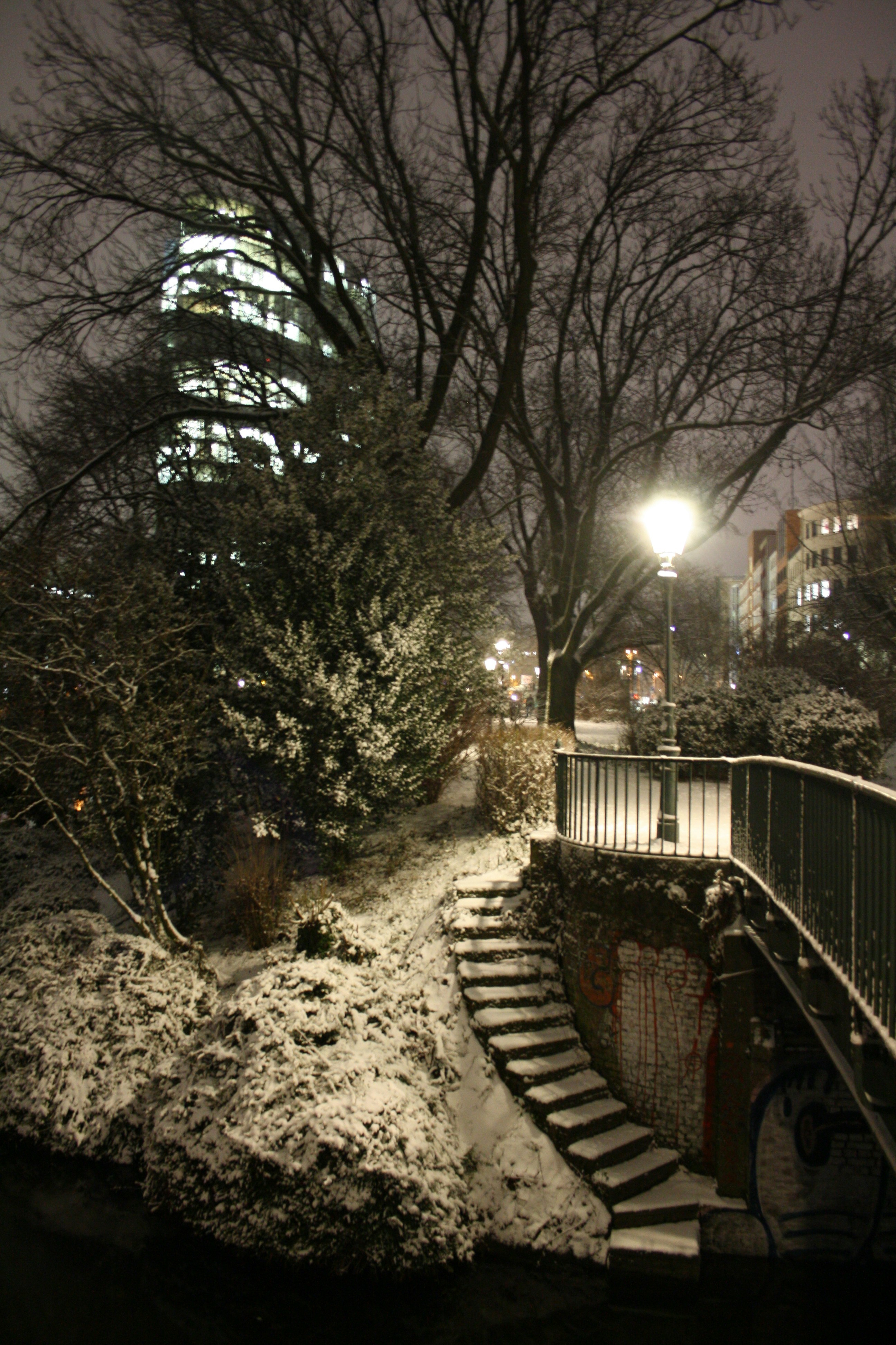 a snowy night in a city with a spiral staircase