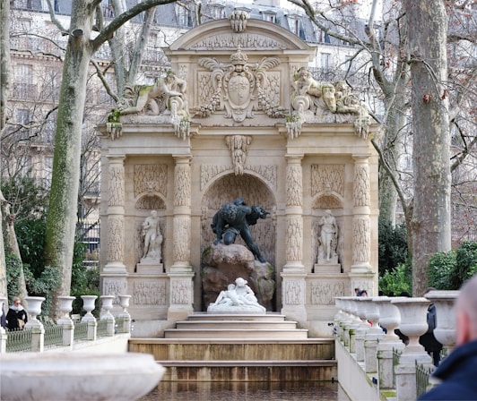 a fountain in a park with statues and trees