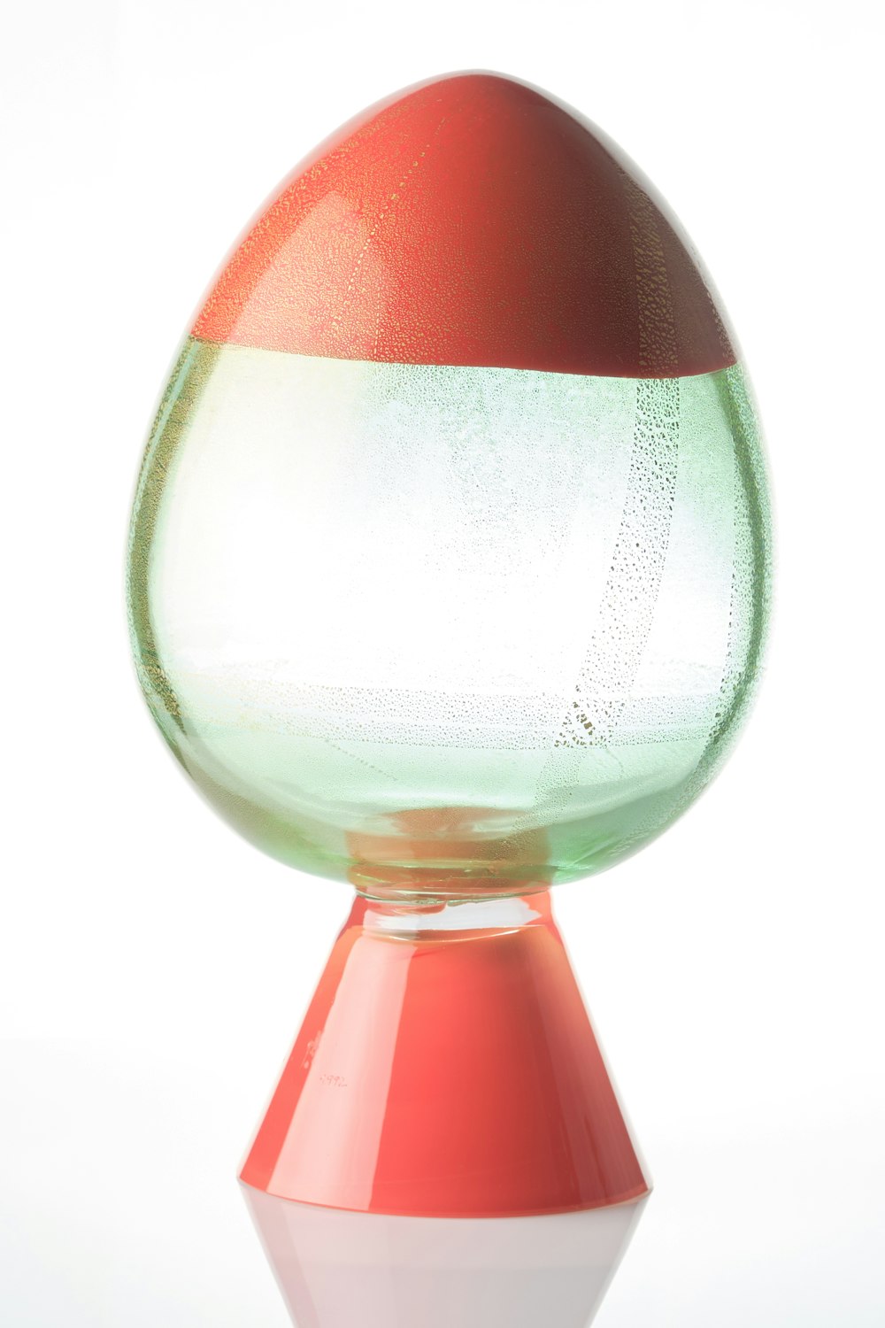 a red, white, and green vase sitting on top of a table