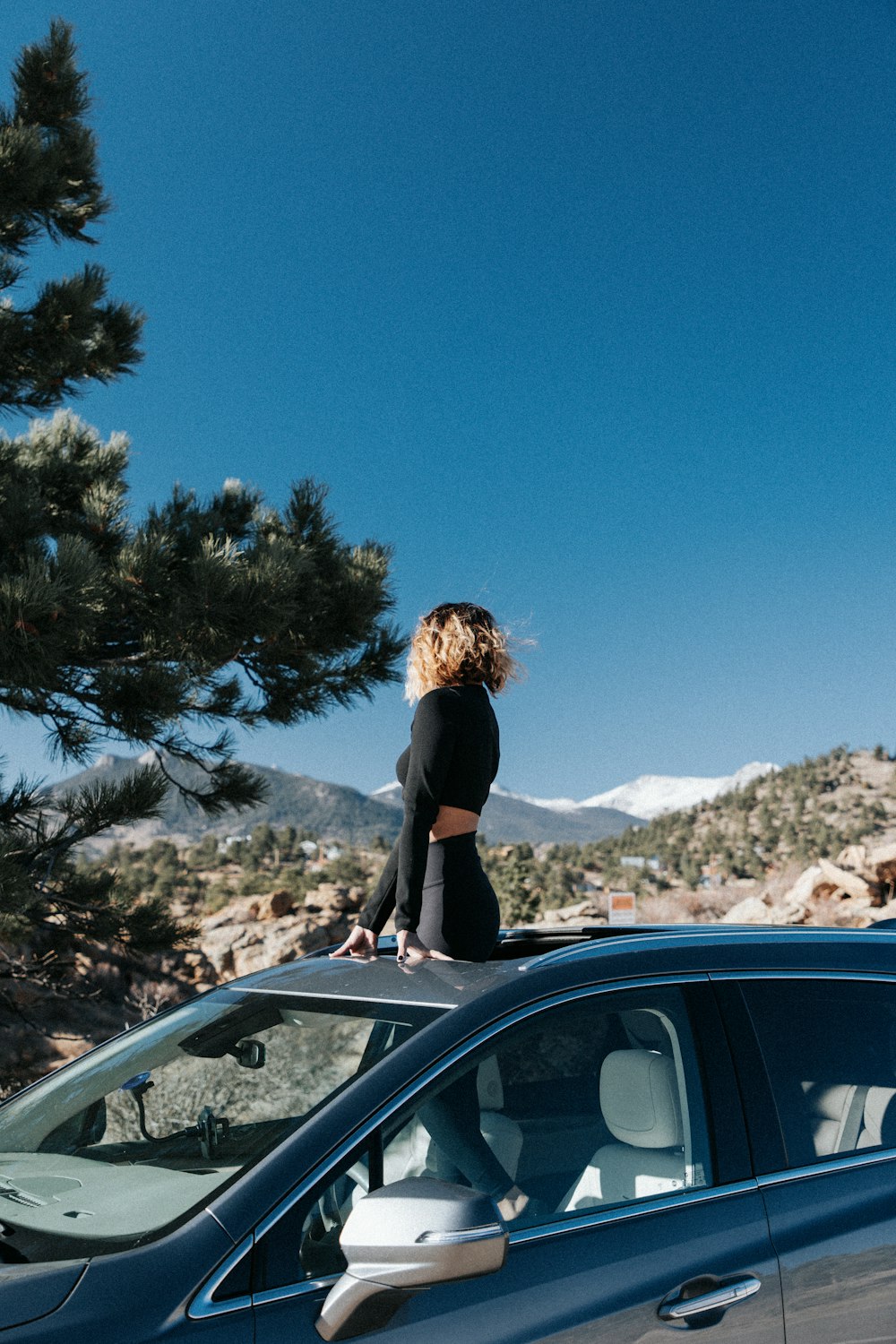 a woman standing on the hood of a car