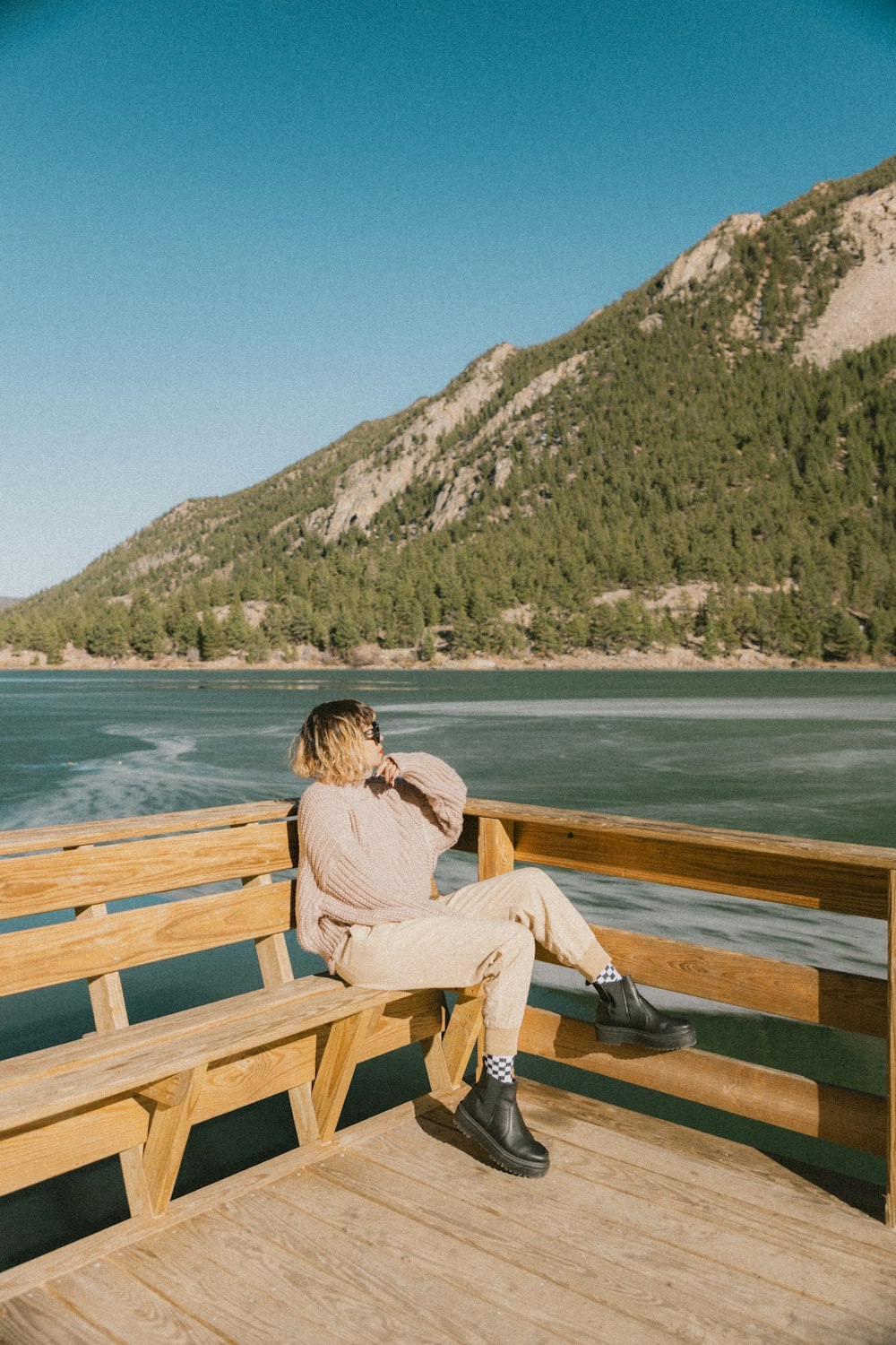 Eine Frau sitzt auf einer Holzbank neben einem Gewässer