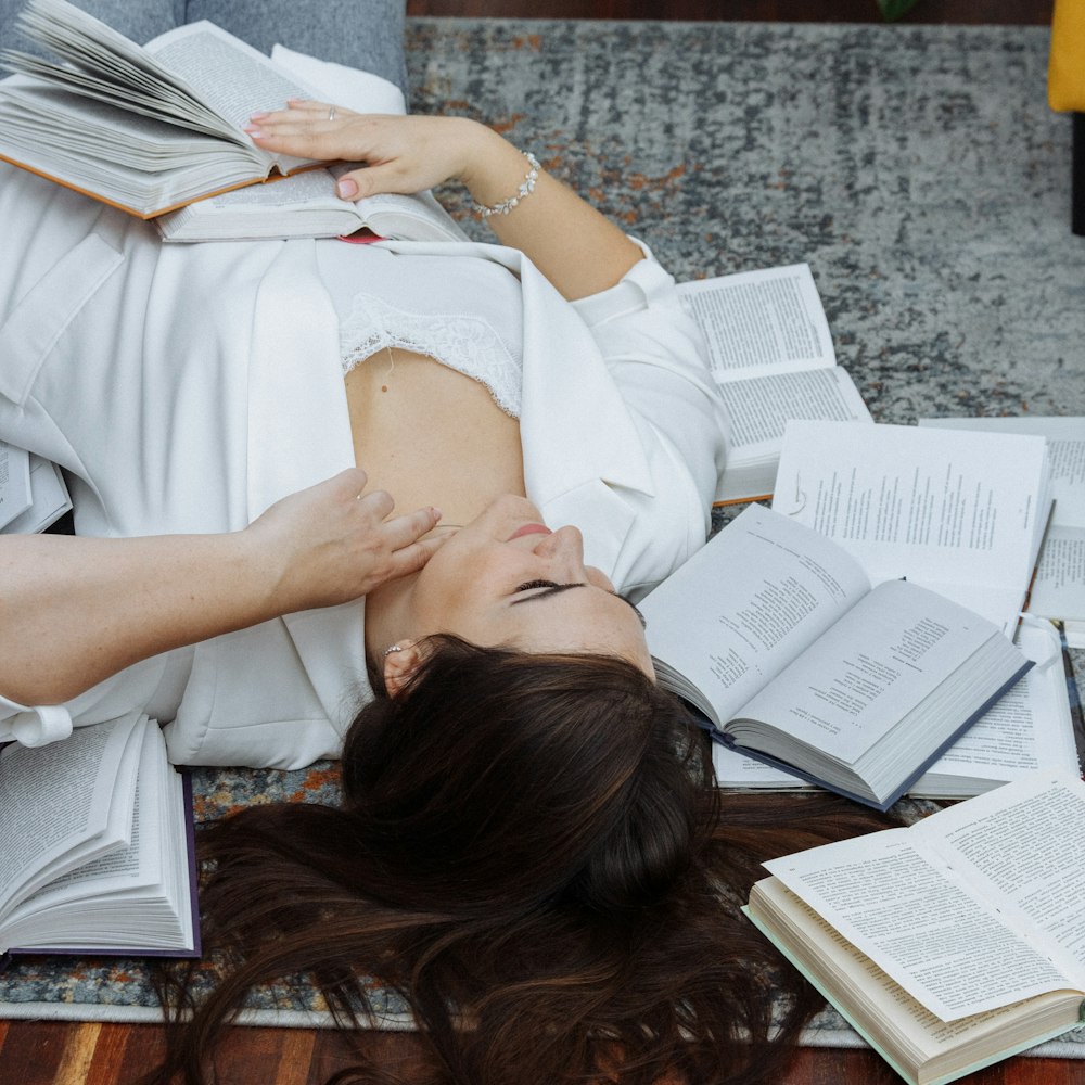 a woman laying on the floor with a lot of books