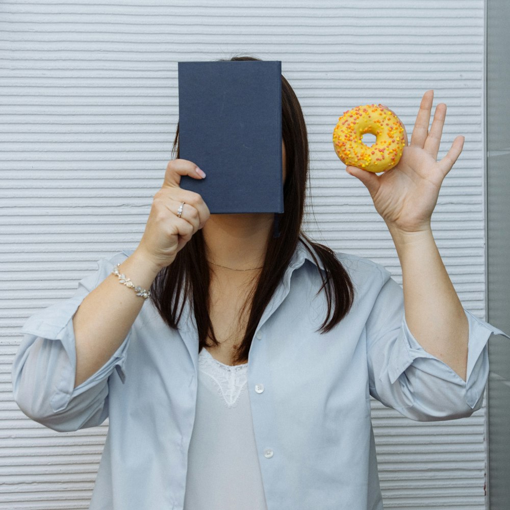 a woman holding a book and a doughnut