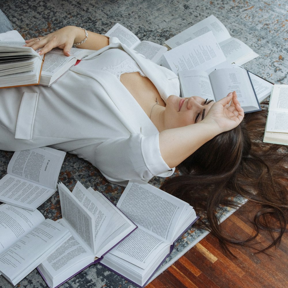 a woman laying on the floor with a lot of books