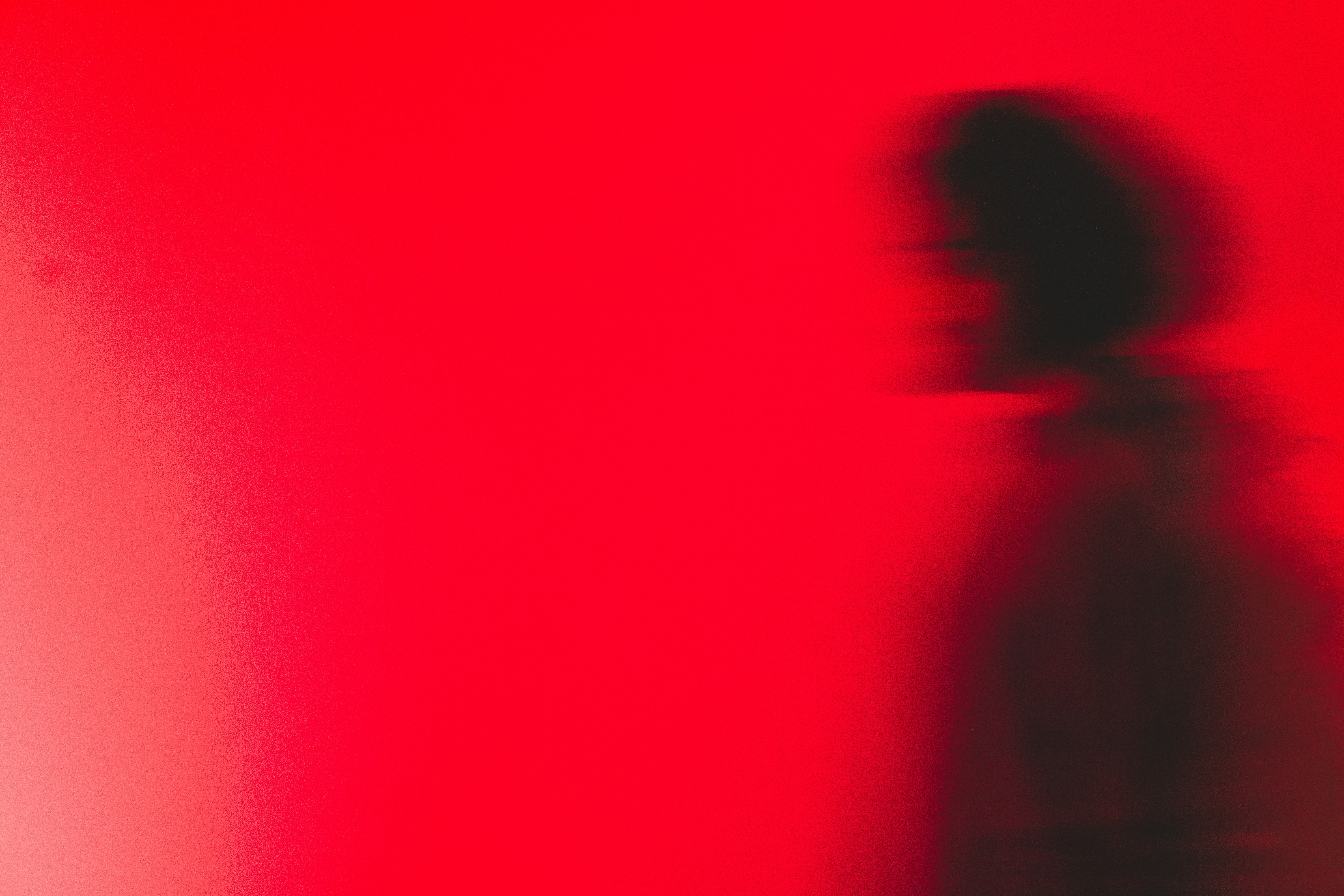 a blurry image of a person standing in front of a red wall