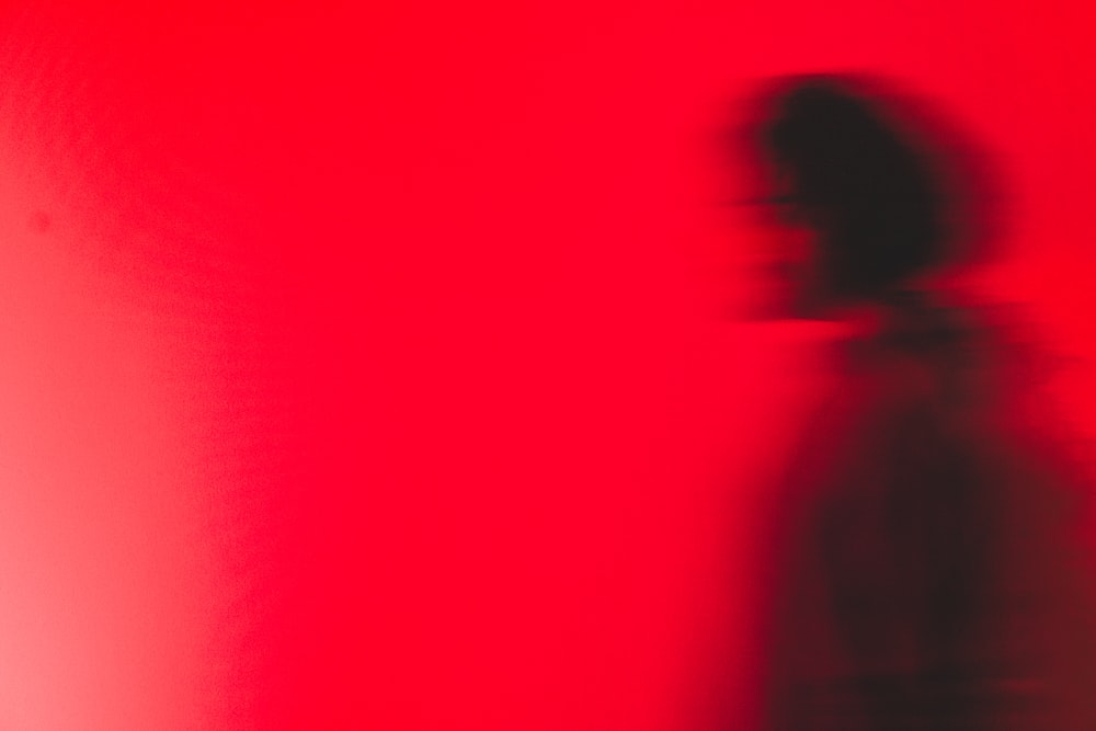 una imagen borrosa de una persona parada frente a una pared roja
