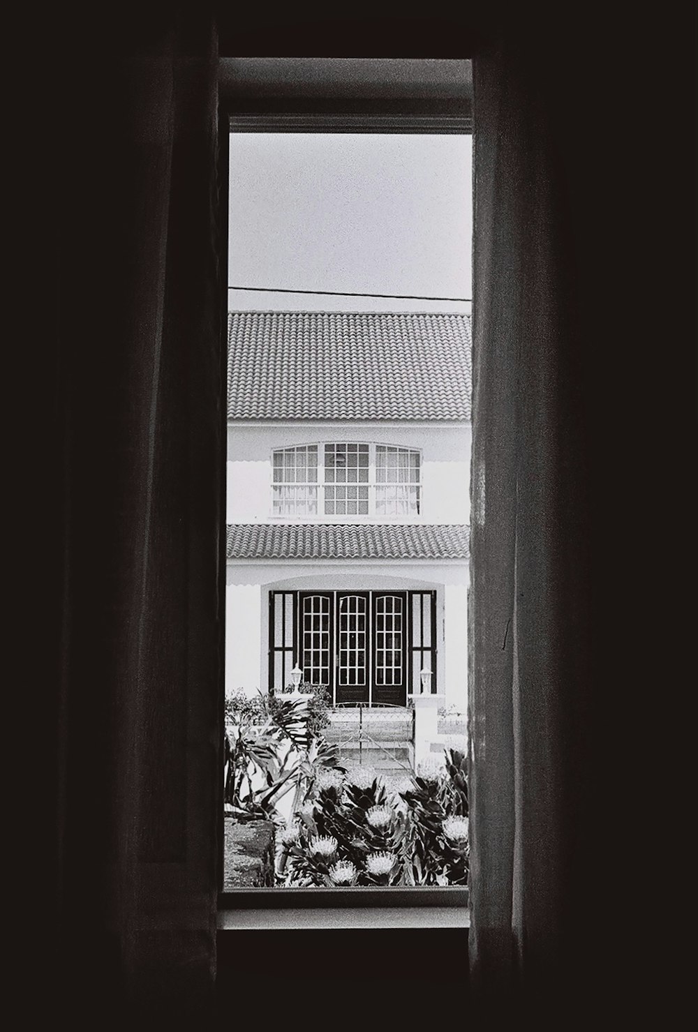 창문을 통해 보이는 집의 흑백 사진