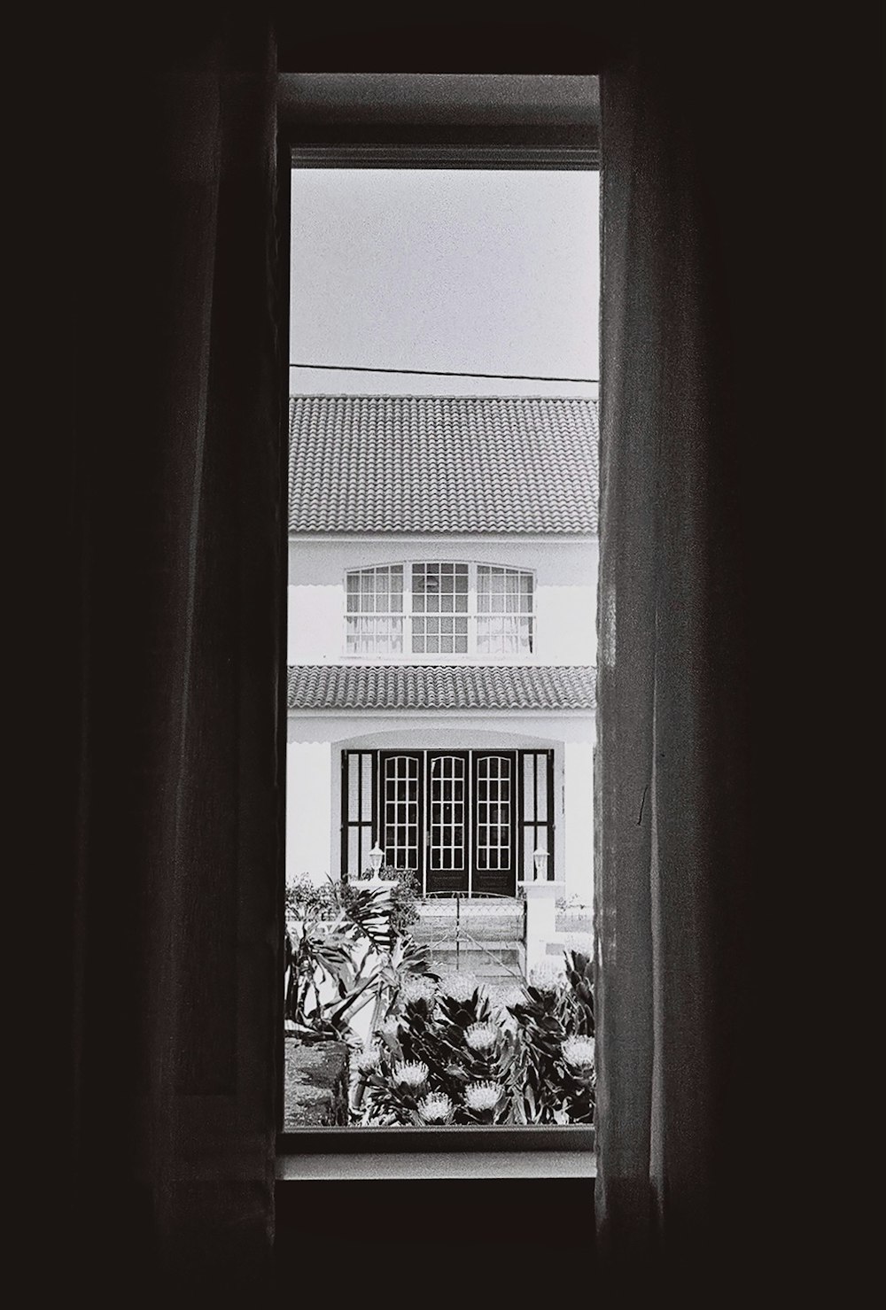 Una foto en blanco y negro de una casa a través de una ventana