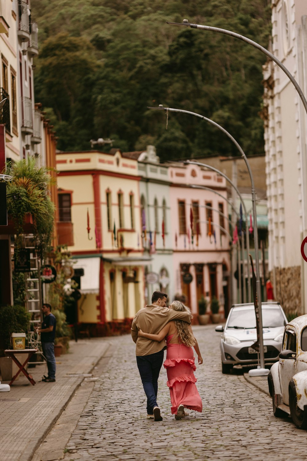 a man and a woman walking down a cobblestone street