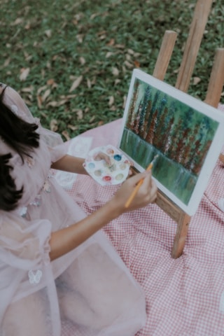 a little girl painting a picture on a easel