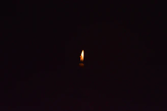a single candle is lit in the dark