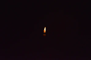 a single candle is lit in the dark
