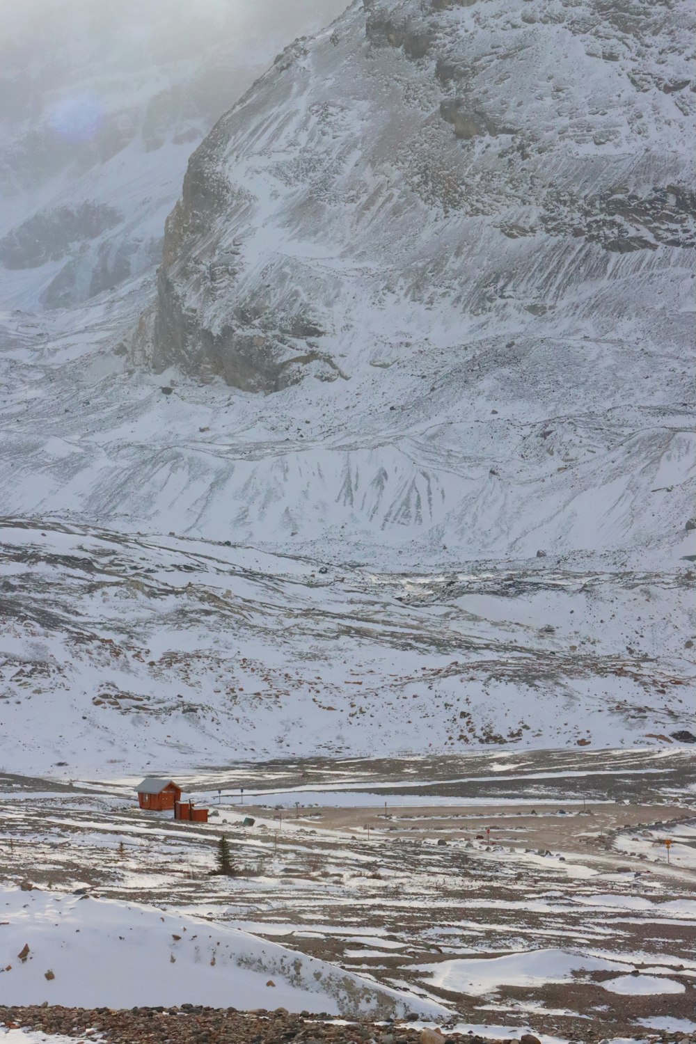 a snow covered mountain with a red truck in the foreground